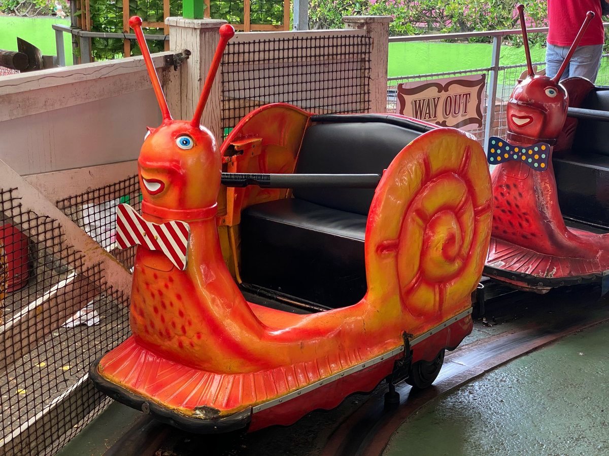 A red and orange snail car with a striped bow tie waiting on the track at Joyland in Great Yarmouth