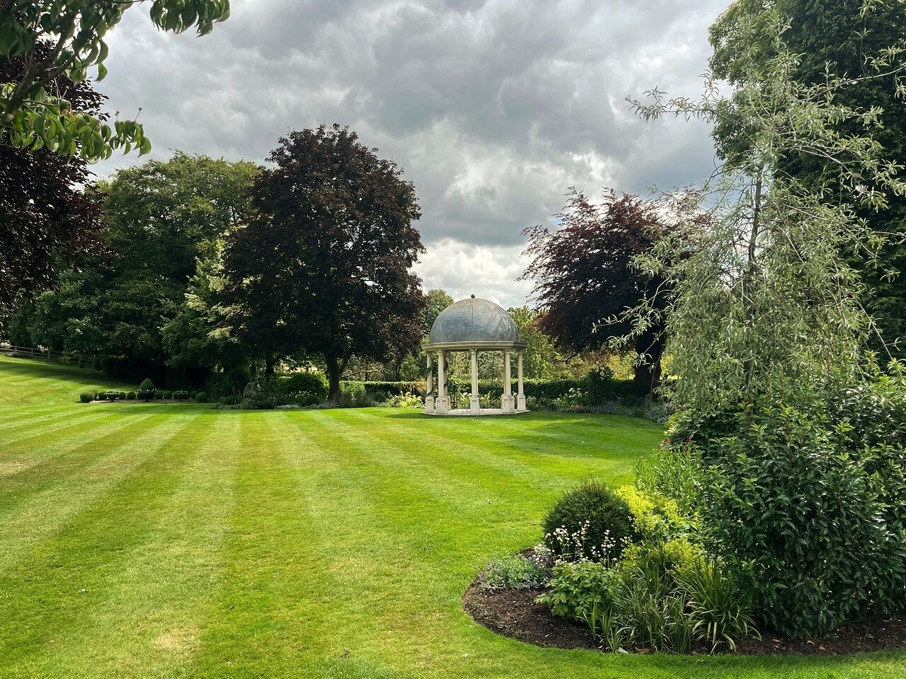 A striped lawn and planted borders in the gardens at Wentbridge House