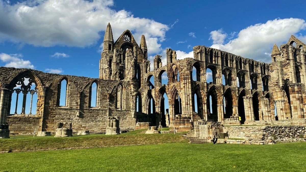 The ruins of Whitby Abbey on the headland, gothic arches against a blue sky with cloud