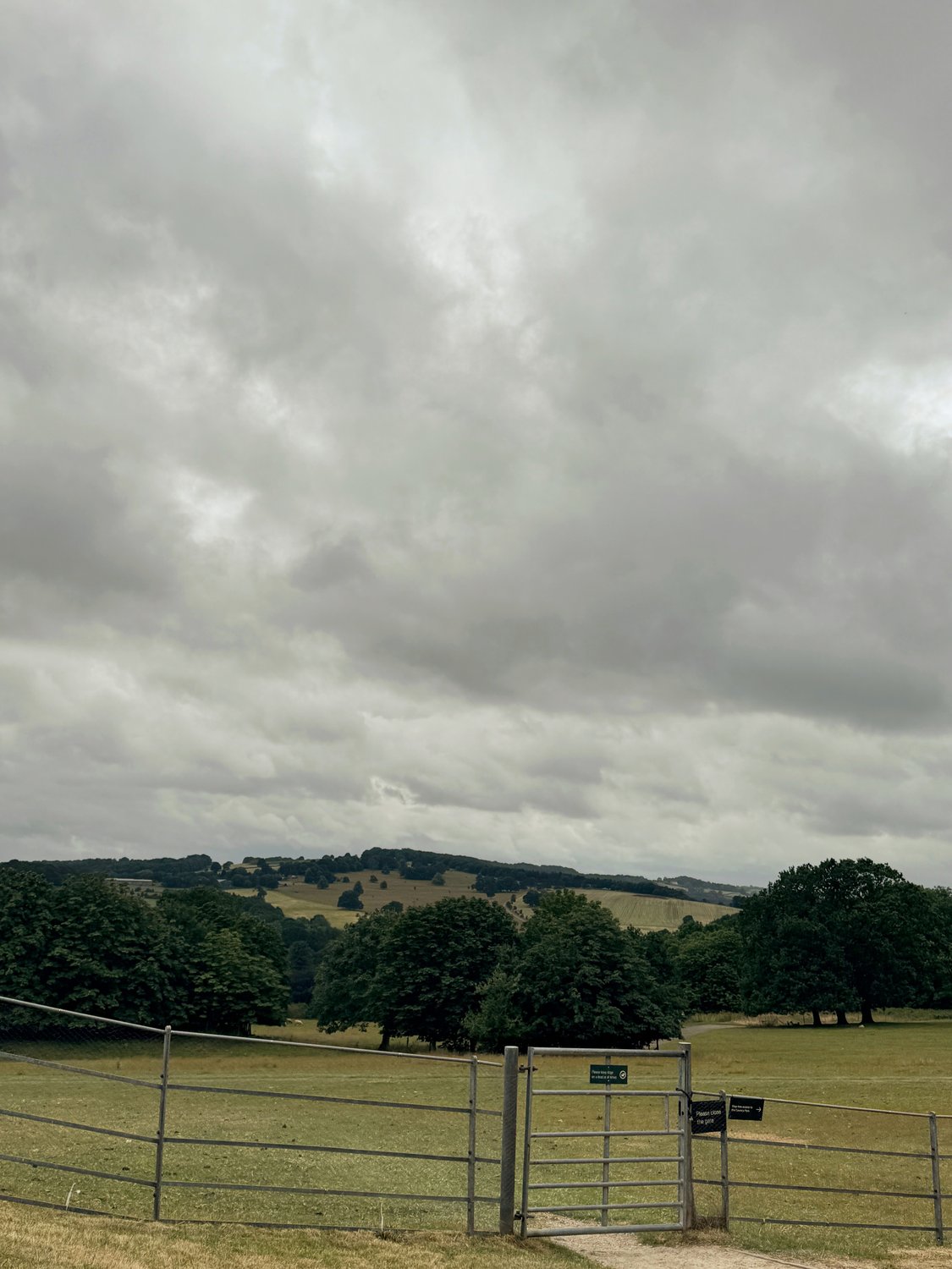 A gate opening onto parkland at Yorkshire Sculpture Park with wooded hills beyond